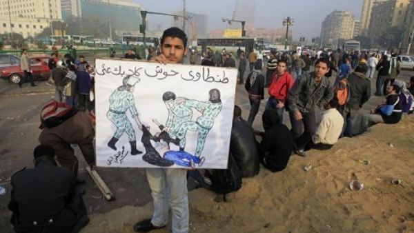 متظاهر مصري يحمل لافتة عليها صورة الناشطة التي تعرضت للضرب وللتعرية من ملابسها من قبل قوات الامن الاسبوع الماضي
