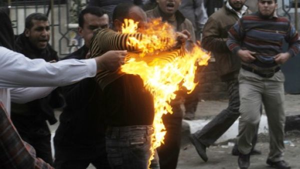 Egyptian members of the Muslim brotherhoods group try to extinguish fire on one of their comrades who he was hit by a molotov cocktail thrown by protesters during clashes in the street that leads to the headquarters of the organization in Cairo on Friday. (Photo: AFP / STR) 