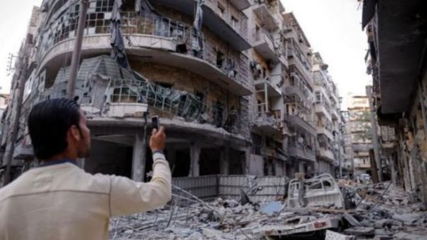 رجل يلتقط صورا بهاتفه النقال للدمار في حي طريق الباب في حلب بشمال سوريا
