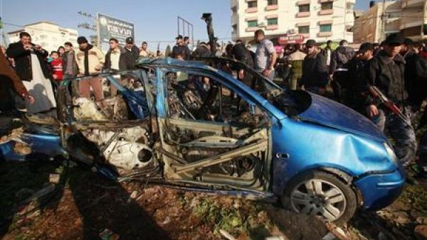 فلسطينون بجوار السيارة التي استهدفتها اسرائيل في مدينة غزة يوم الجمعة
