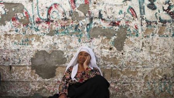 امرأة فلسطينية تجلس على الارض أمام منزلها في خان يونس بقطاع غزة
