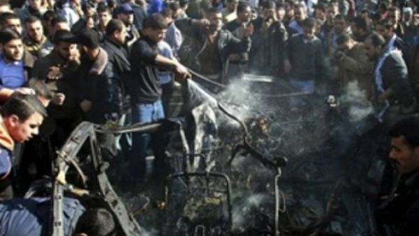 فلسطينيون في موقع الغارة التي استهدفت السيارة الخميس في غزة