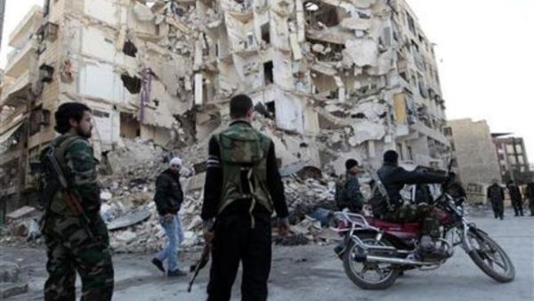 افراد من مقاتلي الجيش السوري الحر يقفون بالقرب من مبنى مدمر في حلب
