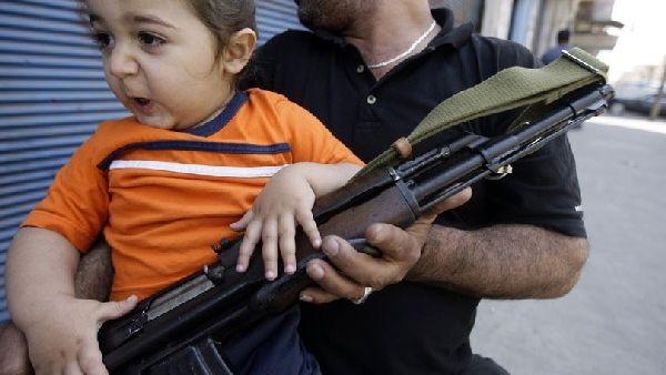A Sunni Muslim gunman sits with his child on Syria Street during fighting in the Bab al-Tebbaneh neighbourhood of the northern Lebanese city of Tripoli. AFP Photo/Getty Images