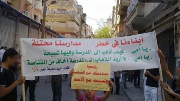 طلاب سوريون يرفعون لافتة أثناء مظاهرة مناهضة لنظام الأسد في حمص ي
