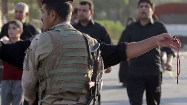 جندي عراقي يفتش المارة في حي الكاظمية شمال بغداد فيما الزوار الشيعة يتوجهون الى ضريح الامام محمد الجواد 
