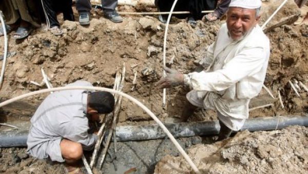 عراقيان يحاولان اصلاح انابيب المياه في الحي الذي يقيمان فيه في بغداد 
