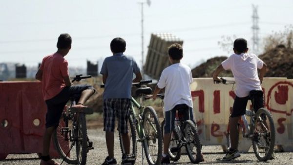 Israeli boys stand with their bicycles as they watch a battery of Iron Dome, a short-range missile defence system, positioned on the outskirts of Tel Aviv on August 30, 2013. (AFP)