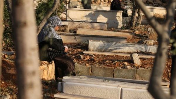 امرأة فلسطينية تجلس عن قبور اقاربها في مقبرة في مدينة رام الله في الضفة الغربية في اول ايام عيد الاضحى
