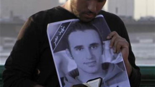 محتج يقرأ القرآن وهو يمسك بصورة خالد خلال الاحتفال بالذكرى الأولى لوفاته في القاهرة 
