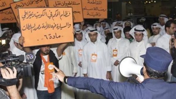 ضابط شرطة يتحدث في مكبر صوت لمحتجين في منطقة الشويخ بالعاصمة الكويت 
