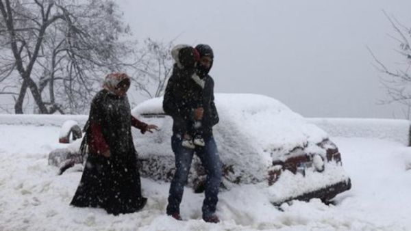 عائلة تسير وسط الثلوج في قرية صوفر شرق لبنان