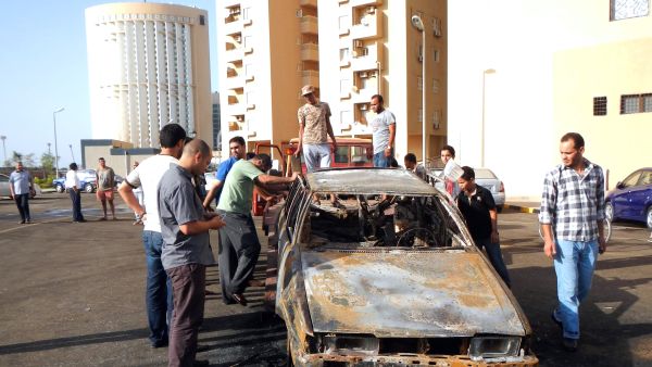 Men examine a car destroyed in a blast near embassies in Tripoli (AFP / MAHMUD TURKIA)