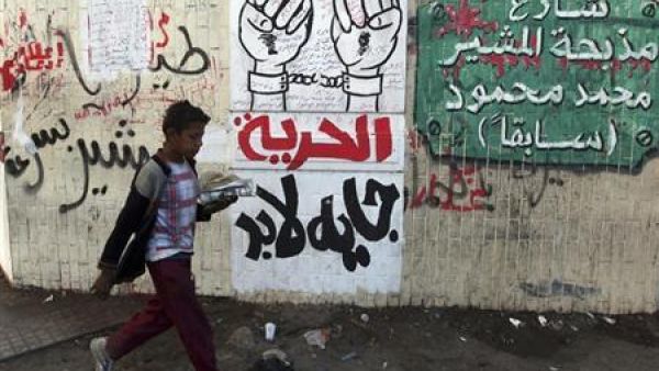 صبي يمر أمام رسوم وكتابة على حائط في القاهرة تنتقد المشير والمجلس العسكري 