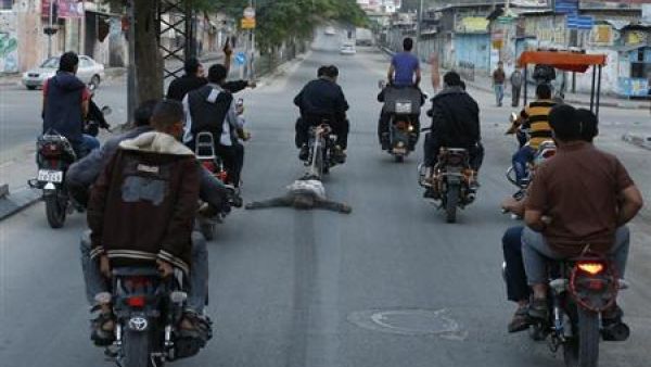 مسلحون فلسطينيون يقودون دراجات نارية يحتفلون بسحل جثة شخص يشتبه انه متعاون مع اسرائيل بعد ان قتلوه في غزة يوم 20 نوفمبر تشرين الثاني 2012
