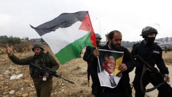 فلسطيني يحمل صورة لمانديلا خلال احتجاج ضد المستوطنات اليهودية في النبي صالح بالضفة الغربية
