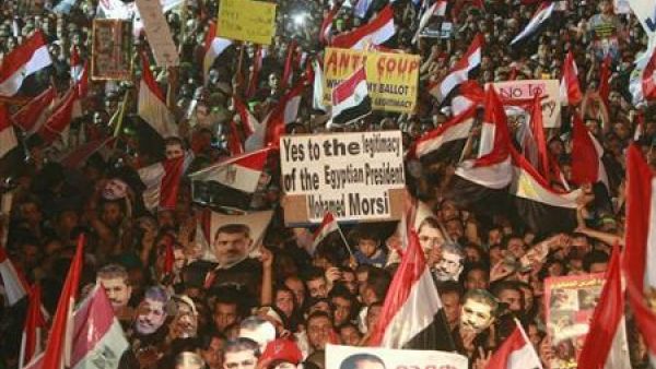 اعضاء من جماعة الاخوان المسلمين وانصار الرئيس المعزول محمد مرسي يضعون اقنعة لمرسي ويلوحون بالاعلام المصرية في ميدان رابعة العدوية في القاهرة
