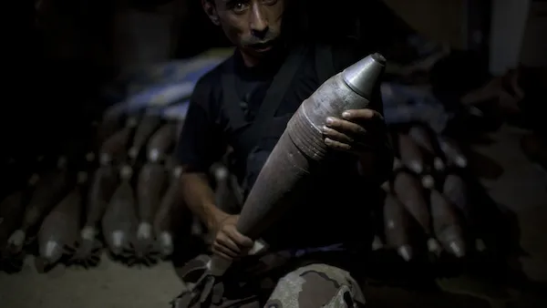 A rebel fighter holds an improvised mortar shell, one of many stacked at a factory in the city of Aleppo, Syria's commercial capital, on July 7, 2013. (Source: AFP/JM LOPEZ)