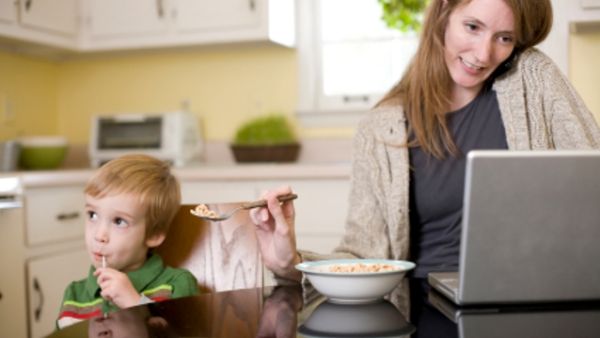 Mothers are often expected to be the best multi-taskers: but here the mother might miss the child's mouth altogether as she juggles work and feeding.
