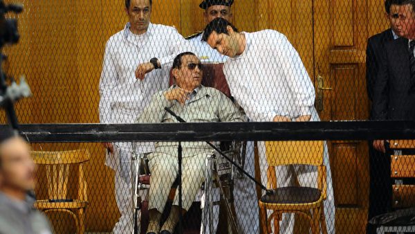 Egyptian toppled president Hosni Mubarak and his two sons Alaa (R) and Gamal stand behind bars during their trial at the Police Academy on September 14, 2013 in Cairo (AFP)