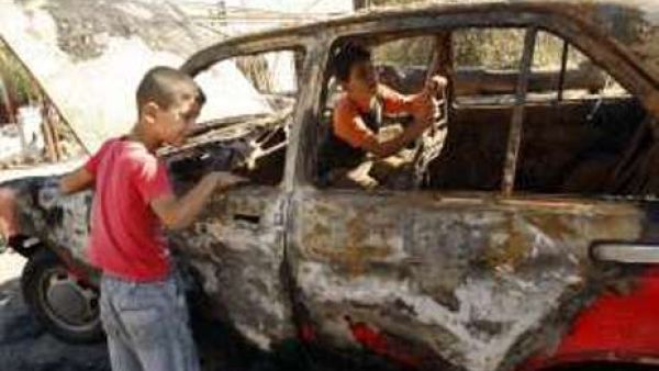 طفلان فلسطينيان يتفقدان سيارة والديهما المحروقة في نابلس