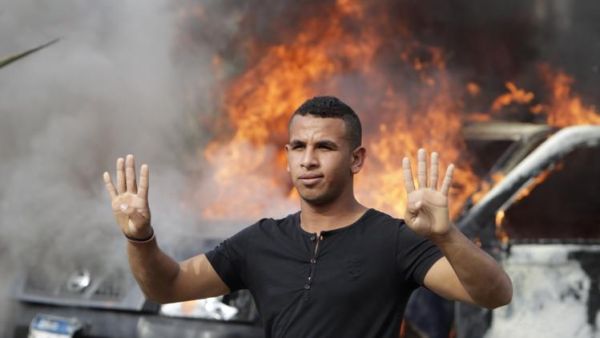 طالب من انصار مرسي يقف امام عربة محترقة للشرطة في ميدان النهضة في القاهرة
