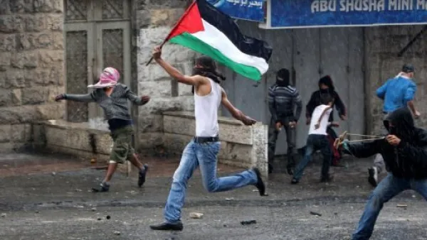  شاب يحمل العلم الفلسطيني ويرشق القوات الاسرائيلية بالحجارة في ذكرى "النكبة" في مخيم شعفاط للاجئين الفلسطينيين
