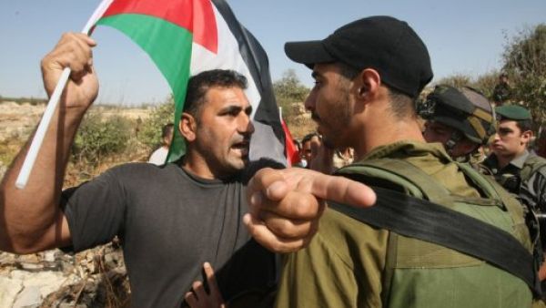 جندي اسرائيلي يوقف متظاهرين اسرائيليين واجانب وفلسطينيين قرب قرية بيت عمر في الضفة
