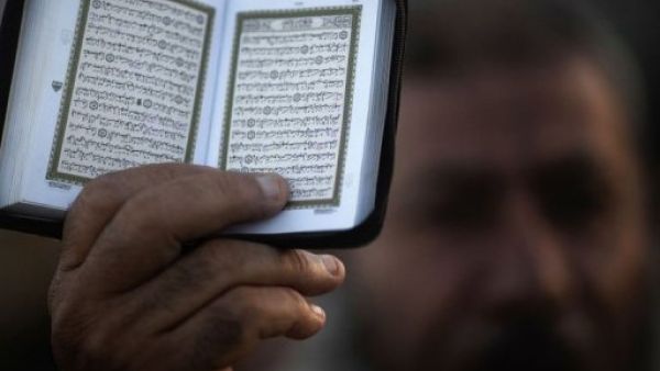 رجل مسلم يحمل نسخة من القران الكريم