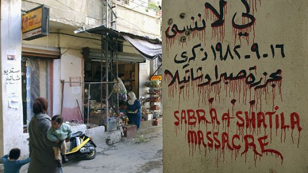 A Palestinian woman passes by a sign marking the 1982 Sabra and Shatila massacre in Beirut, Lebanon [GALLO/GETTY]