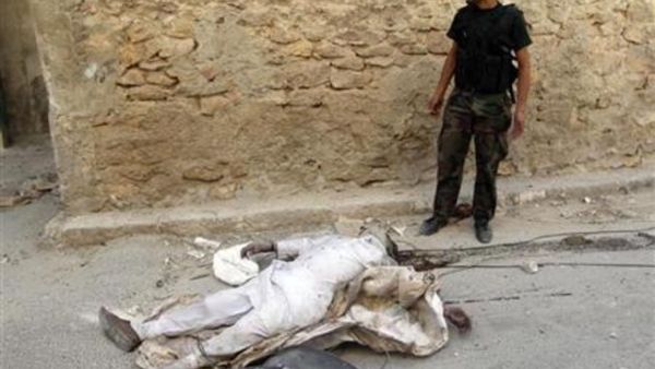 مقاتل من الجيش السوري الحر يقف بجوار جثة شخص قتل في تبادل اطلاق النار بحي صلاح الدين بوسط المدينة
