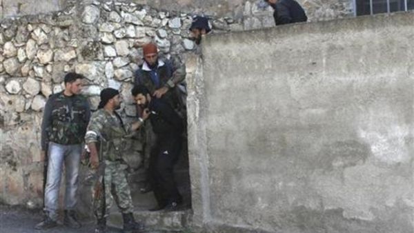 افراد من الجيش السوري الحر يعتقلوان رجلا يشتبه في انه من القوات المؤيدة للحكومة في احد المدن التابعة لادلب
