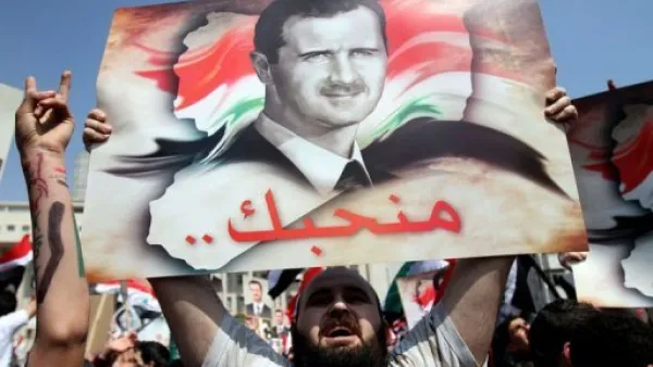 متظاهر مؤيد للاسد يحمل صورته خلال تظاهرة في دمشق