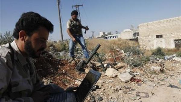 مقاتل من الجيش السوري الحر المعارض يستخدم كمبيوتر محمول واخر يستعد لاطلاق قذيفة مورتر قرب مطار عسكري تسخدمه قوات الرئيس السوري بشار الاسد في حلب
