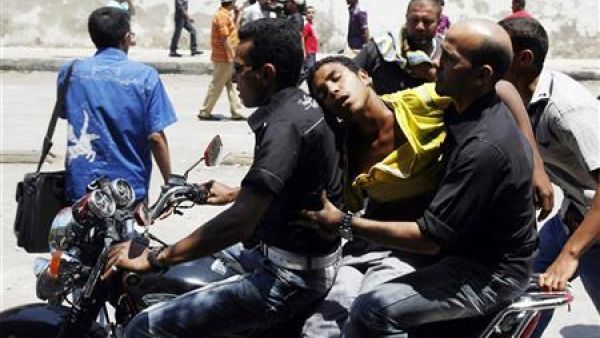 مصريان يحملان على دراجة نارية شابا أصيب بقنبلة غاز مسيل للدموع أثناء مواجهات مع الشرطة امام وزارة الداخلية 