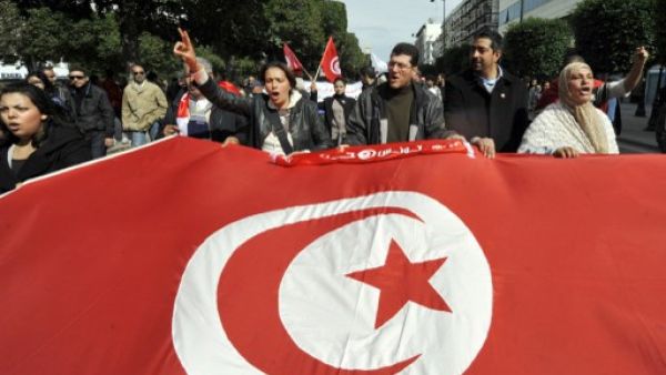 Tunisian people wave a giant national flag during a demonstration to mark the 40th day of mourning after the death of anti-Islamist opposition leader Chokri Belaid (featured on poster) on Saturday on the Habib Bourguiba Avenue in Tunis. (AFP / Fethi Belaid)