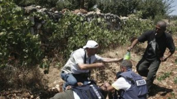 مصور وكالة رويترز يتلقى مساعدة زملائه بعد انفجار قنبلة صوتية قرب اذنه
