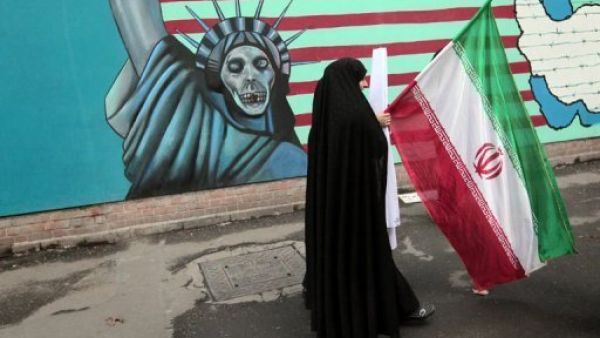ايرانية تحمل علما وطنيا وتمر امام رسم مندد بالولايات المتحدة على جدار السفارة الاميركية السابق في طهران 

