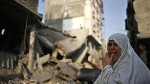 امراة فلسطينية تقف امام منزل مدمر اثر غارة اسرائيلية في غزة