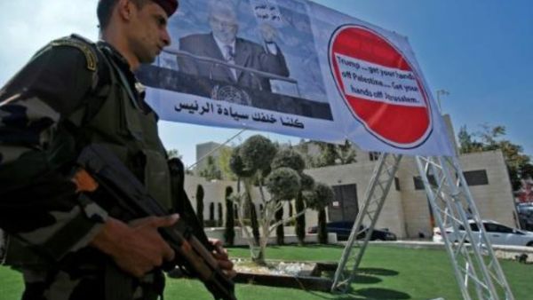 رجل أمن فلسطيني أمام ملصق للرئيس محمود عباس خلال تظاهرة ضد قرار واشنطن وقف مساعدتها لوكالة الانروا في بيت لحم

