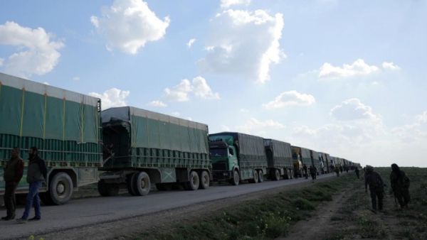 مقاتلون من قوات سوريا الديمقراطية يسيرون بجانب شاحنات بالقرب من قرية الباغوز في دير الزور بسوريا
