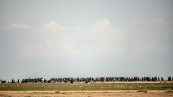 نساء وأطفال ينتظرون في حقل بعد فرارهم من الباغوز آخر معقل لتنظيم الدولة الاسلامية في سوريا

