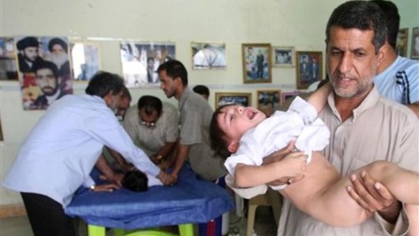 عراقي يحمل طفلا مصاب 