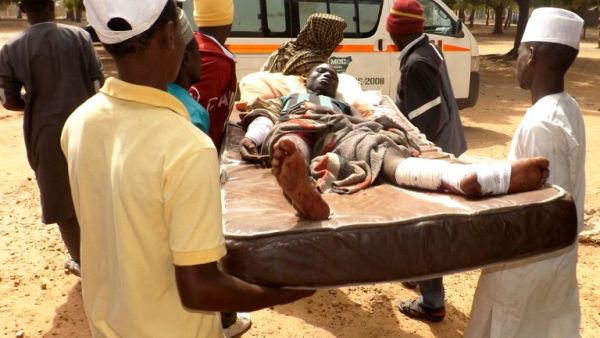 Relatives carry a man injured in a suicide blast in the northeast Nigerian town of Potiskum on Jan. 12. No one claimed responsibility but the attacks bore the hallmark of Boko Haram militants. (AFP/Aminu Abubakar)