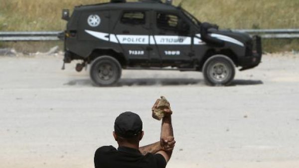 متظاهر فلسطيني يحمل حجارة في مواجهة دورية اسرائيلية
