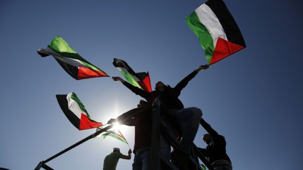 Palestinians wave flags during a demonstration in the West Bank. (AFP/File)
