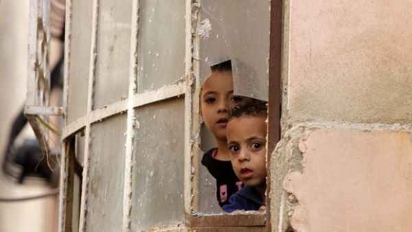 Palestinian children look through a window at Israeli soldiers conducting searches in the Palestinian al-Fawwar refugee camp, south of the West Bank city of Hebron. (AFP/File)