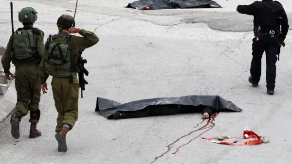 Israeli soldiers and police gather around the body of a Palestinian assailant who was shot in head by an Israeli soldier as he lay wounded on the ground after injuring an Israeli soldier in the West Bank town of Hebron on March 24, 2016. (AFP/Hazem Bader)
