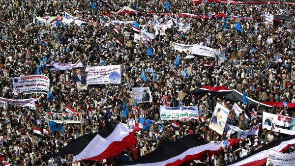 Yemenis wave national flags and hold placards during a protest against the Saudi-led coalition, commemorating one year of the alliance's military campaign against insurgents on March 26, 2016 next to the Monument to the Unknown Soldier in the Yemeni capital Sanaa. (AFP/Mohammed Huwais)