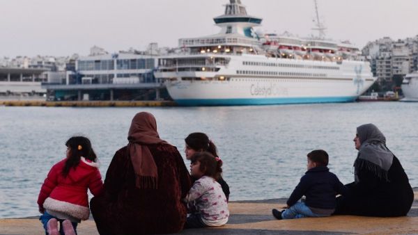 Refugee families sit on February 26, 2016 at a pier in the port of Piraeus, where hundreds of migrants and refugees, many from Syria stay temporarily. (AFP/Louisa Gouliamaki)